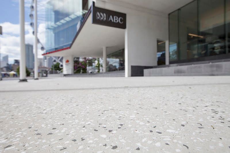Modern building entrance with ABC sign and speckled concrete walkway under an overhang