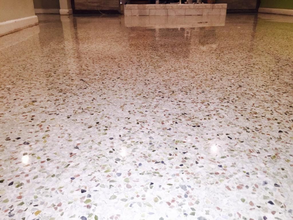 Polished terrazzo floor with speckled stones and a cabinet in the background