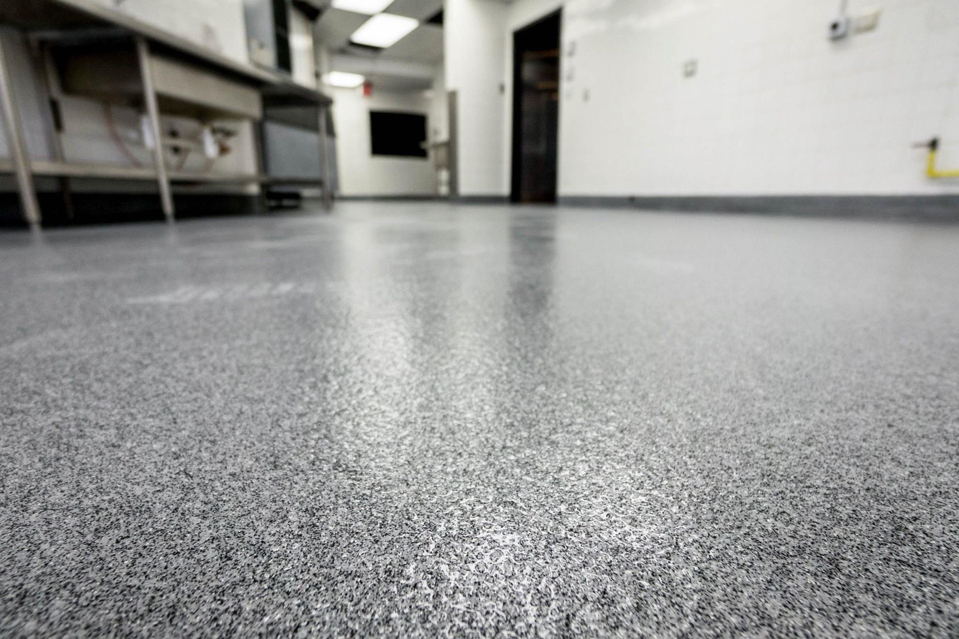 Low-angle view of a clean commercial kitchen with speckled floor and stainless steel counters