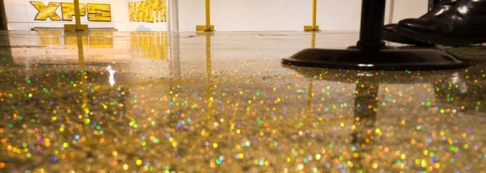 Sparkling gold glitter on a glossy floor with a black stand and a blurred gold logo in the background