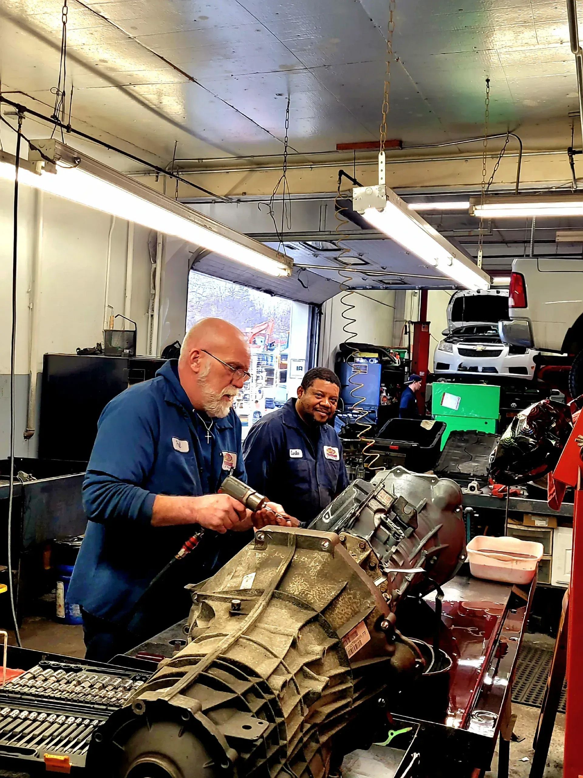 Technicians working on a large mechanical assembly in a workshop, surrounded by tools and equipment.