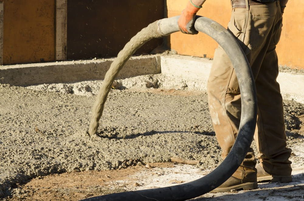 Worker pouring wet concrete from a hose at a construction site for concrete pumping Hunter Valley, NSW