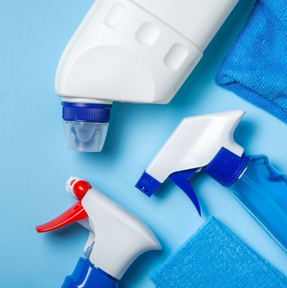 Assorted cleaning spray bottles and disinfectant containers on a blue background