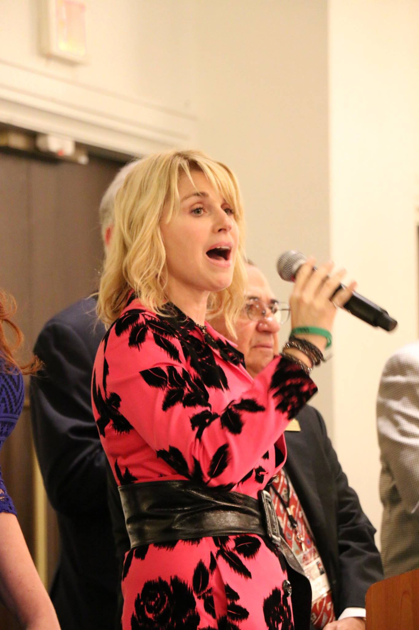 A woman in a pink dress is singing into a microphone.