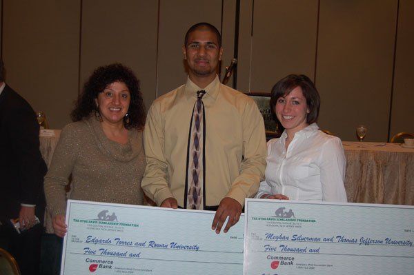 A man and two women are holding two cheques in their hands