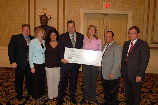 A group of people standing in front of an exit sign holding a check