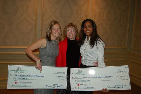 Three women are standing next to each other holding checks