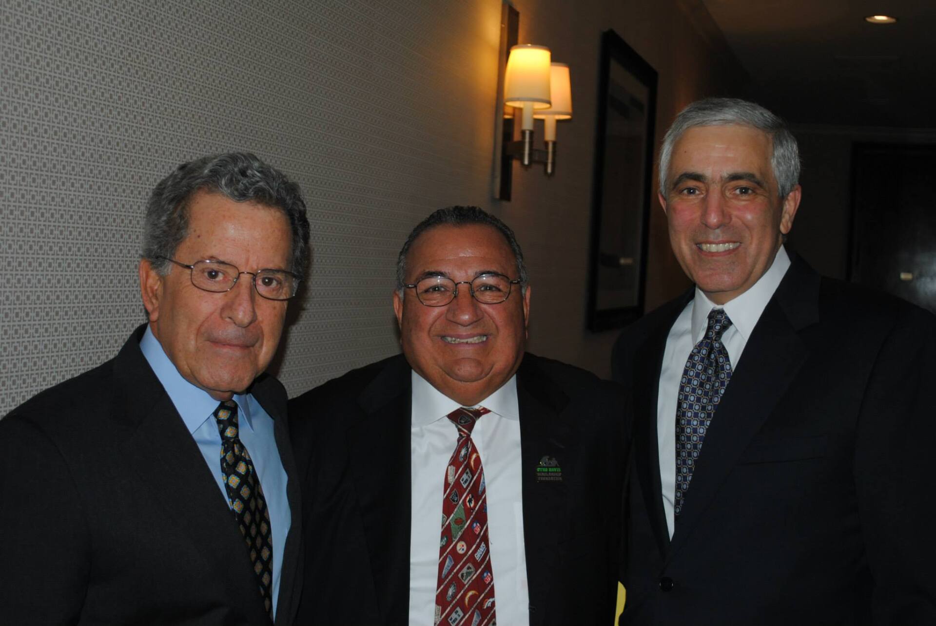 Three men in suits and ties pose for a picture