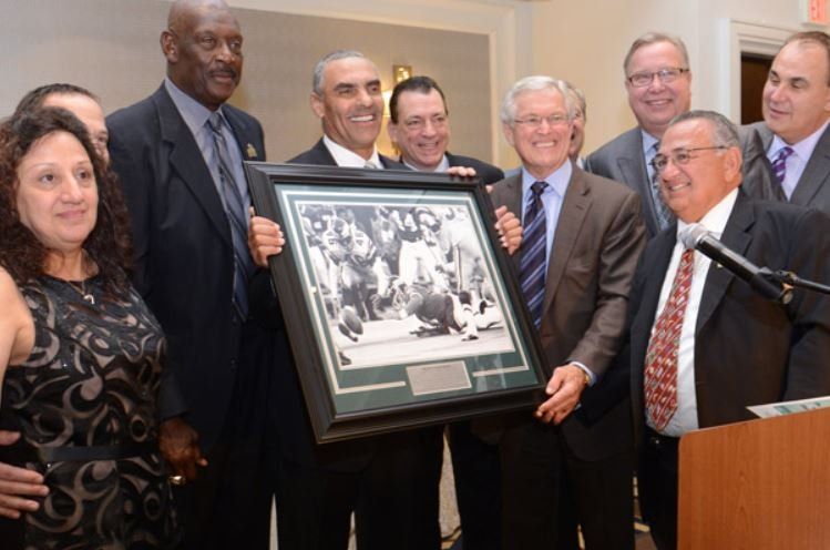 A group of men are holding a framed picture of a boxing match