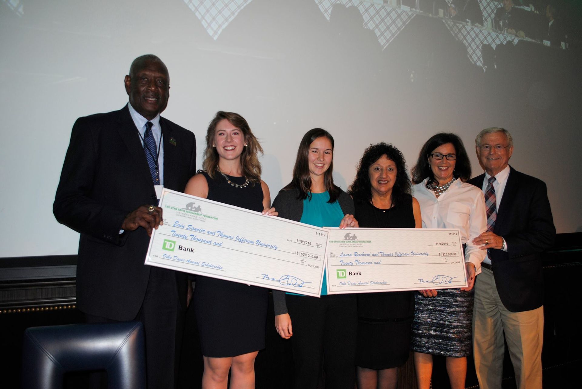 A group of people standing next to each other holding cheques