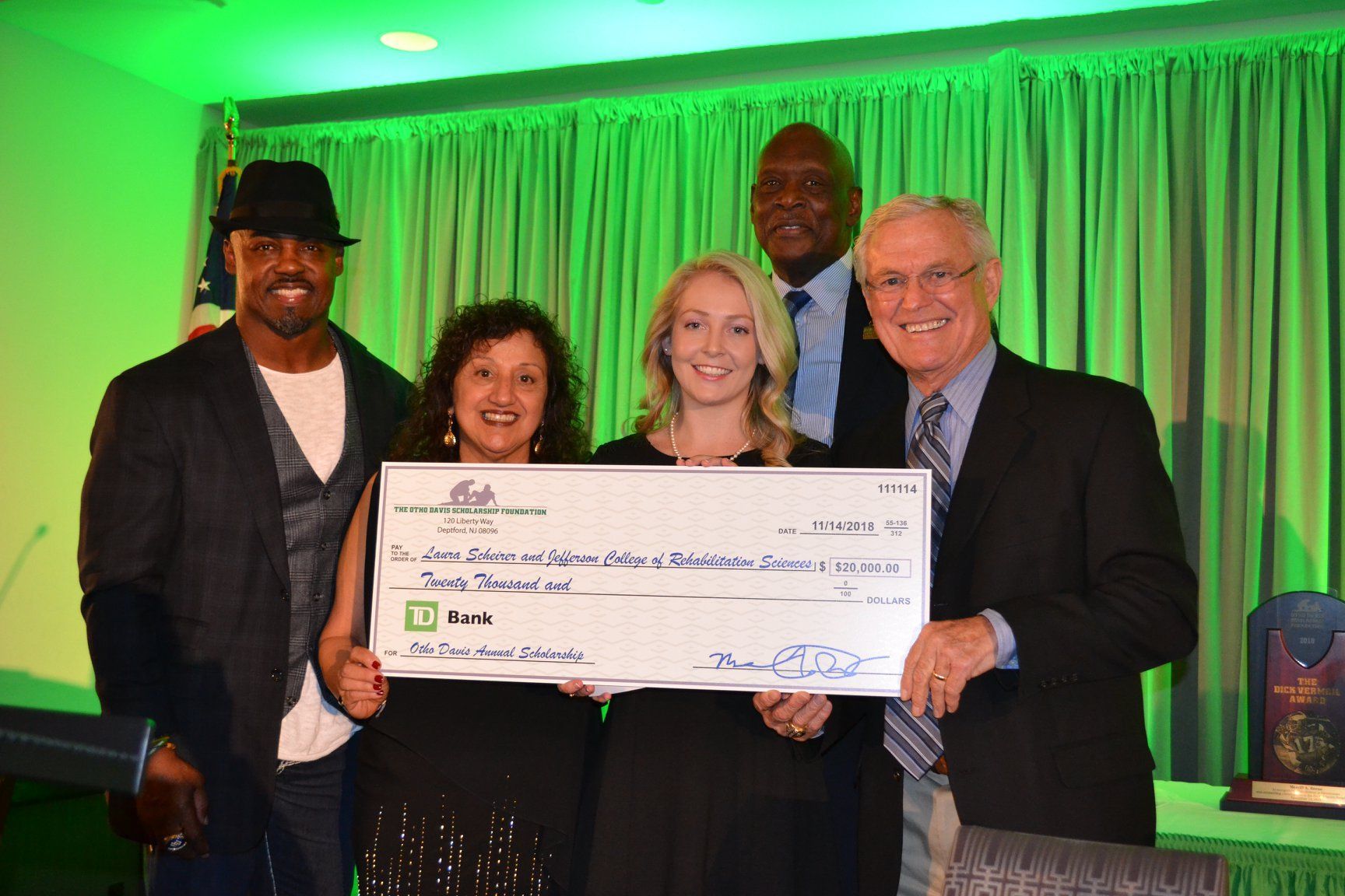 A group of people are posing for a picture while holding a large check.