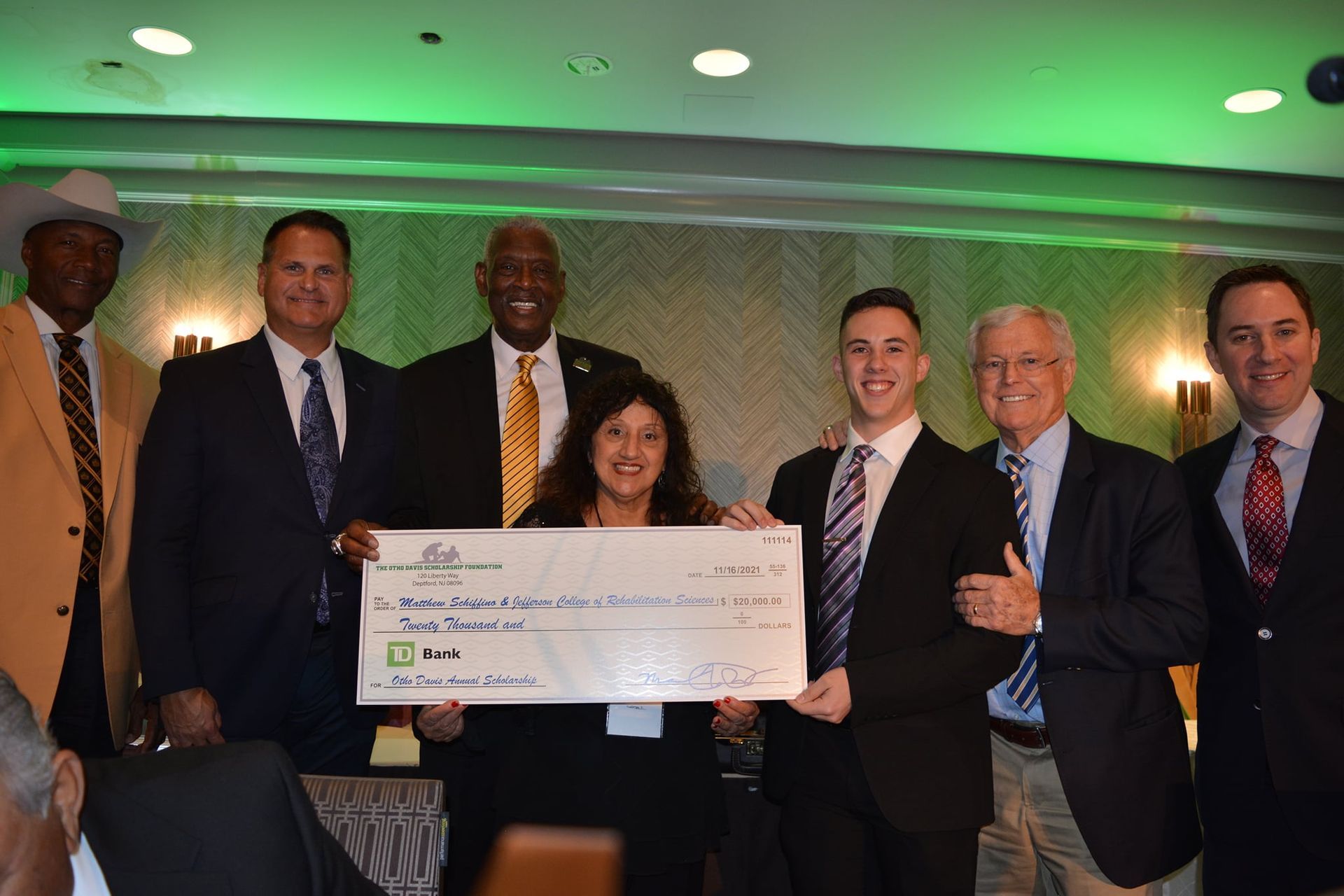 A group of people are posing for a picture while holding a large check.