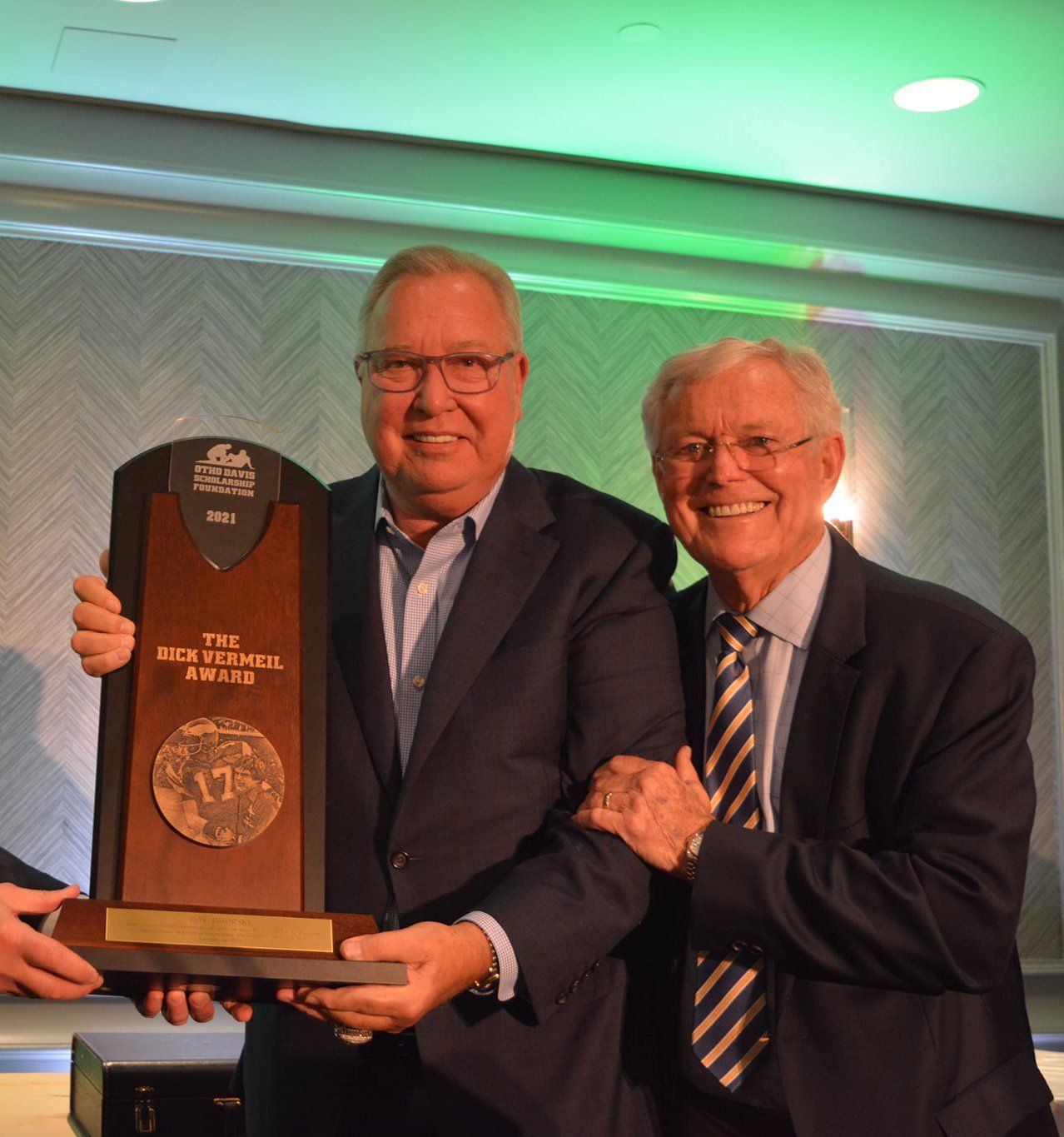 Two men in suits are holding a trophy that says ncaa on it