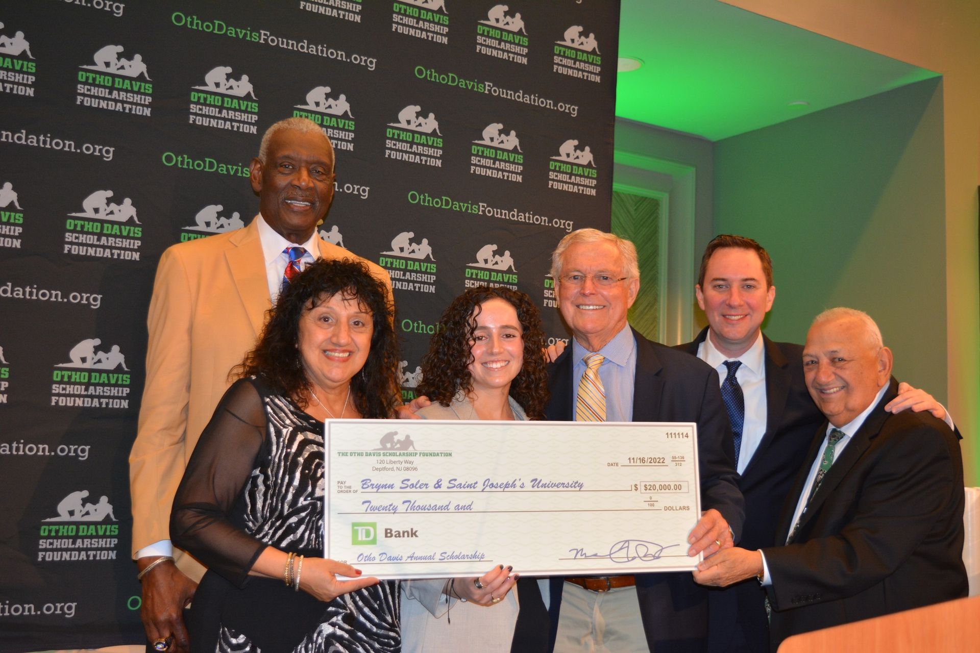A group of people are posing for a picture while holding a large check.