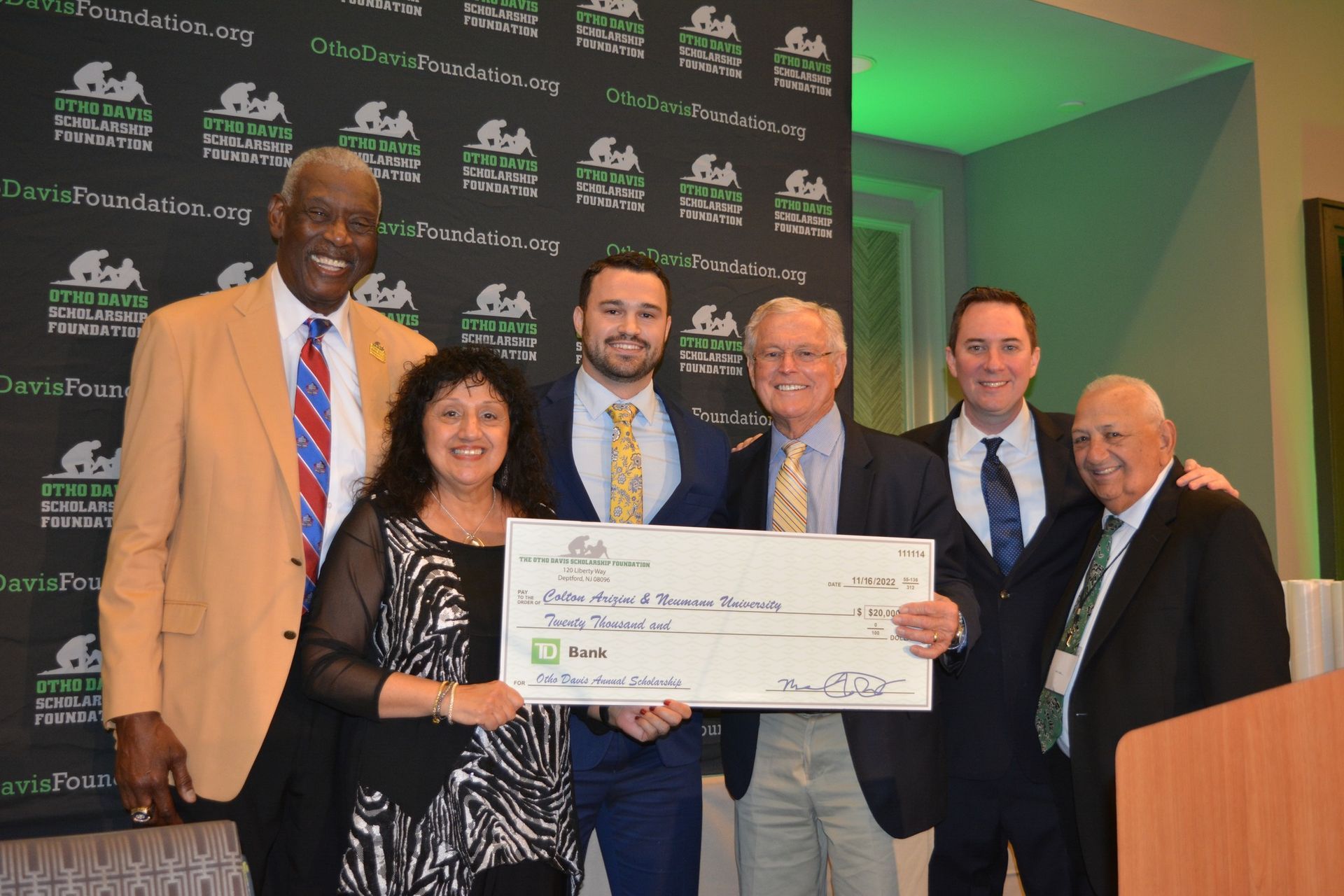 A group of people are posing for a picture while holding a large check.
