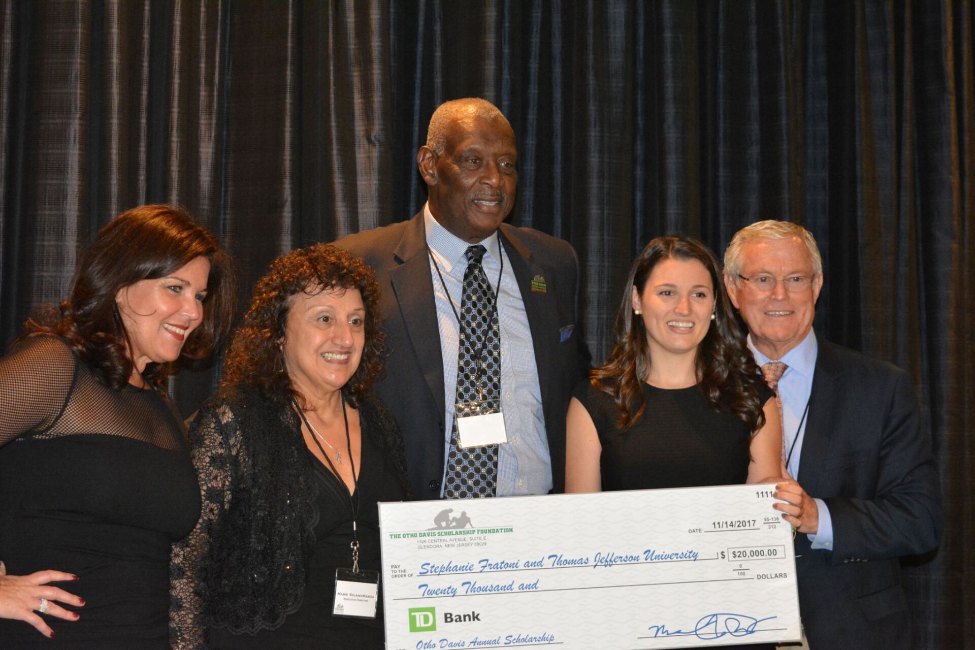 A group of people standing next to each other holding a large check.