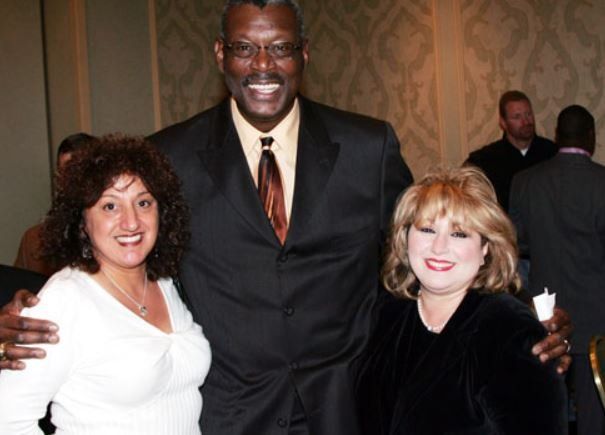 A man in a suit and tie poses with two women