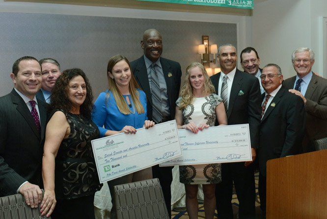 A group of people standing next to each other holding checks.