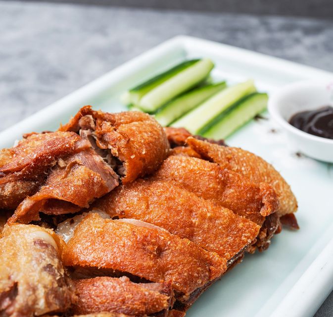 Fried breaded cutlet slices on a plate with cucumber sticks and dipping sauce