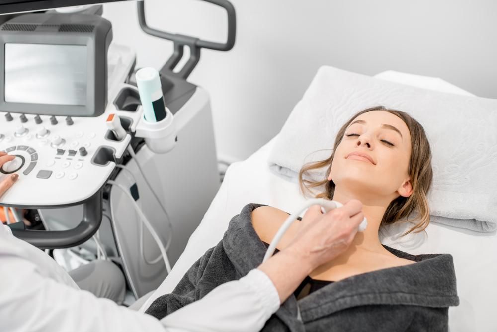 A Woman Is Laying In A Hospital Bed Getting An Ultrasound Of Her Neck — Mall Medical Centre In Alice Springs, NT