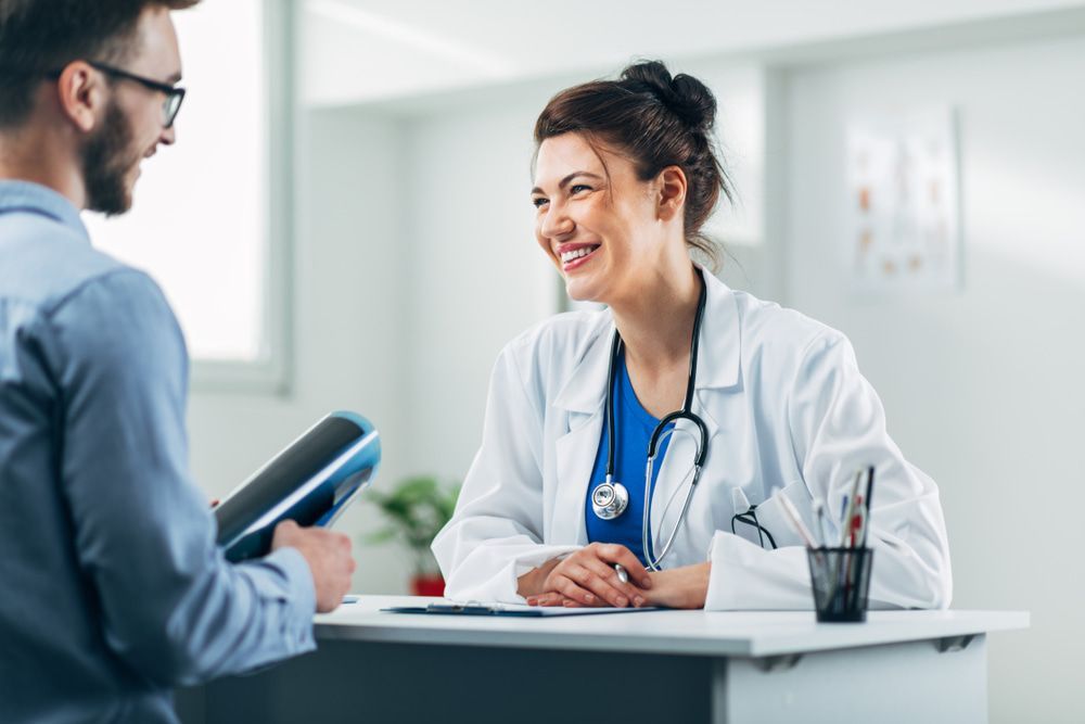 A Doctor Is Sitting At A Desk Talking To A Patient — Mall Medical Centre In Alice Springs, NT