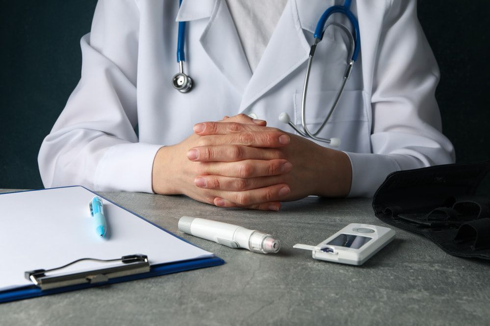 A Doctor Is Sitting At A Desk With Her Hands Folded — Mall Medical Centre In Alice Springs, NT