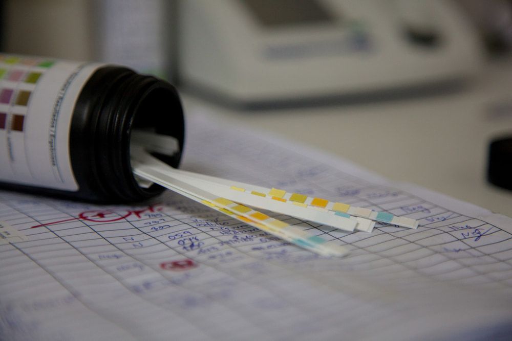 A Bottle Of Urine Test Strips Spilling Out Of It On A Table — Mall Medical Centre In Alice Springs, NT