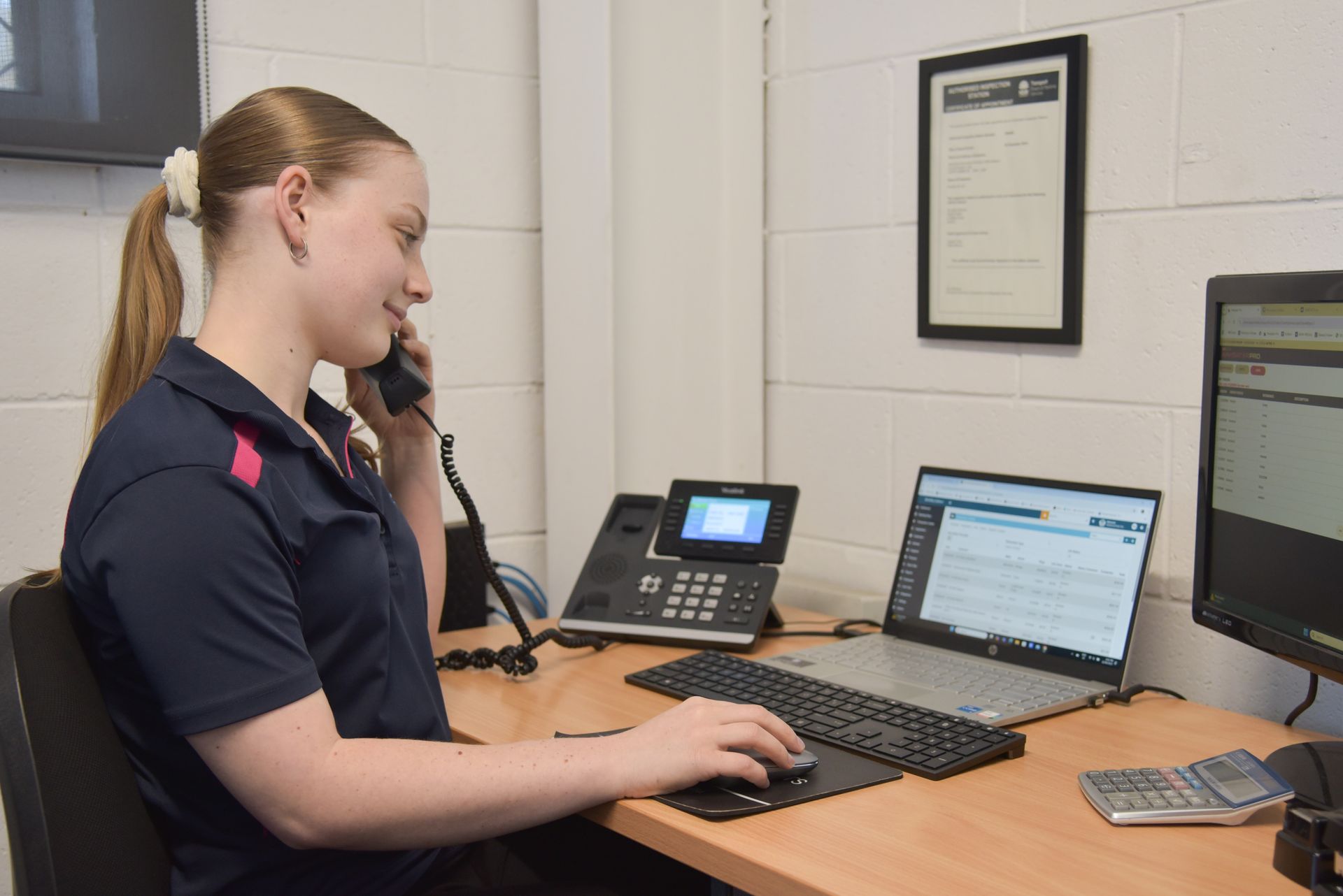 A girl is sitting in an office while on the phone — Advanced Automotive Services in Coffs Harbour, NSW