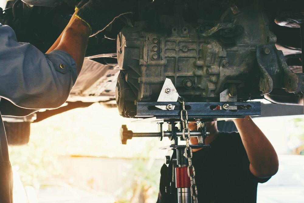 A Man is Working on a Car Engine on a Lift — Advanced Automotive Services in Coffs Harbour, NSW