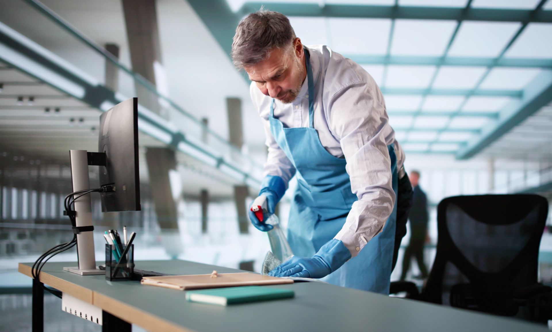 Technician in blue apron inspecting a product on a workbench in a bright industrial workshop