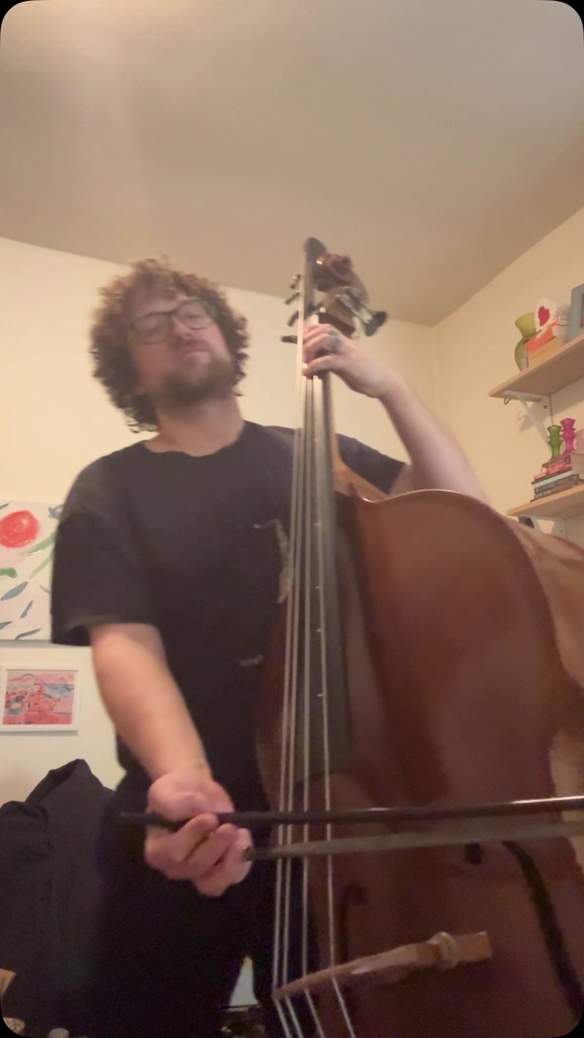 A man is playing a double bass in a room.