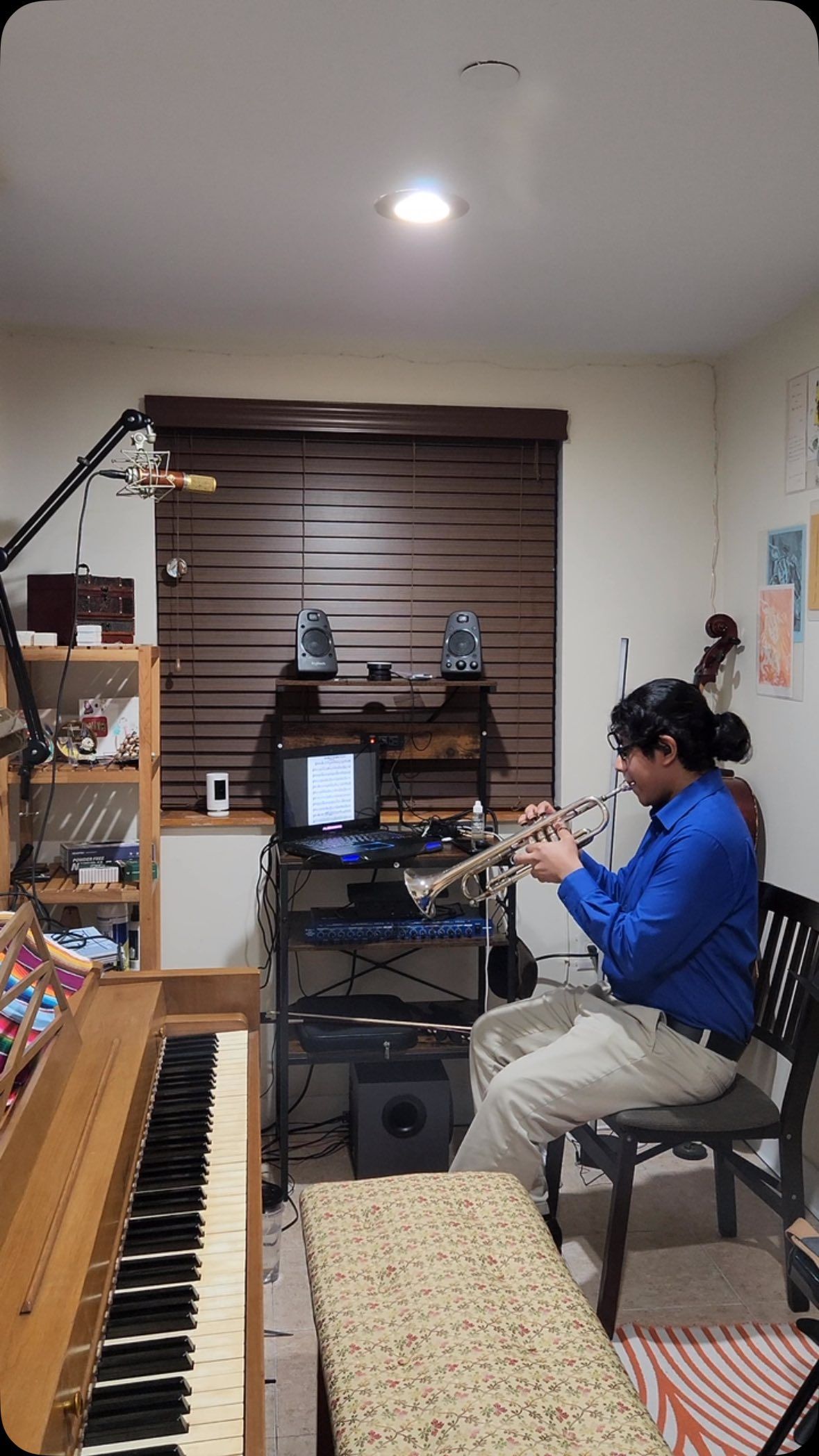 A man is playing a flute in a room next to a piano.