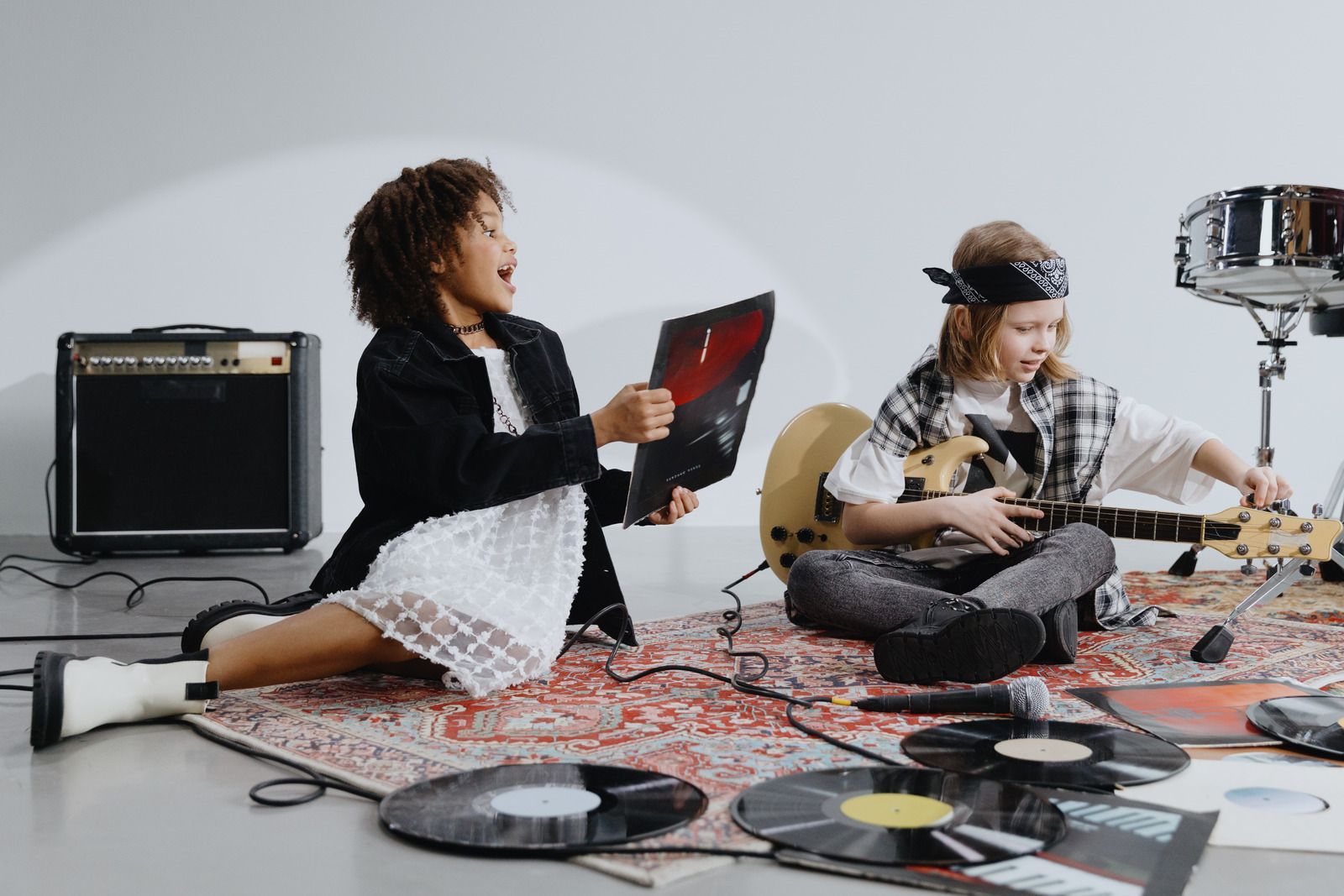 A man with curly hair is playing a guitar in a room.