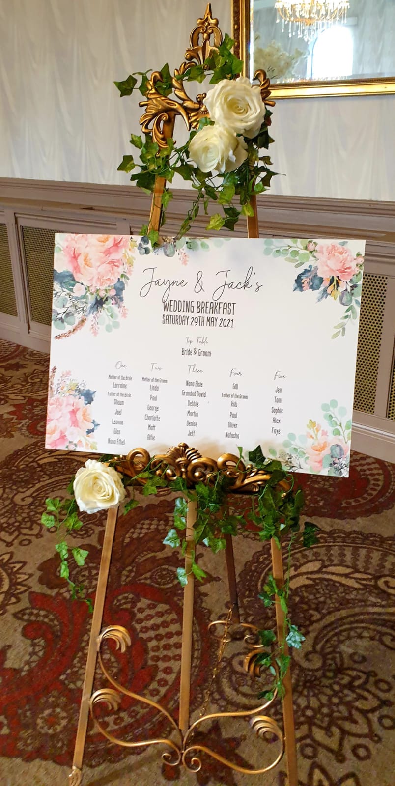 Wedding seating chart on a decorative easel, with floral accents.
