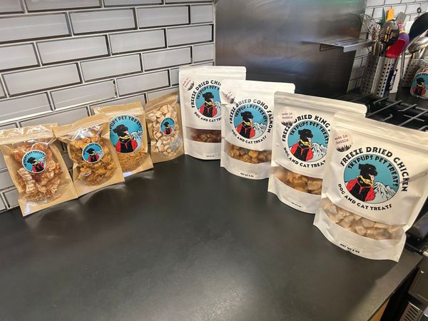 Bags of food product on a counter, with a cartoon logo. Gray tile backsplash.