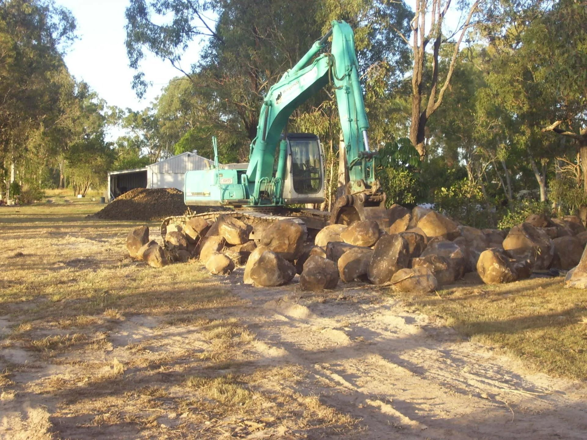 Green Excavator Moving Rocks on A Dirt Lot — A1 Rock This City Truck & Dog Hire In Good Night, QLD