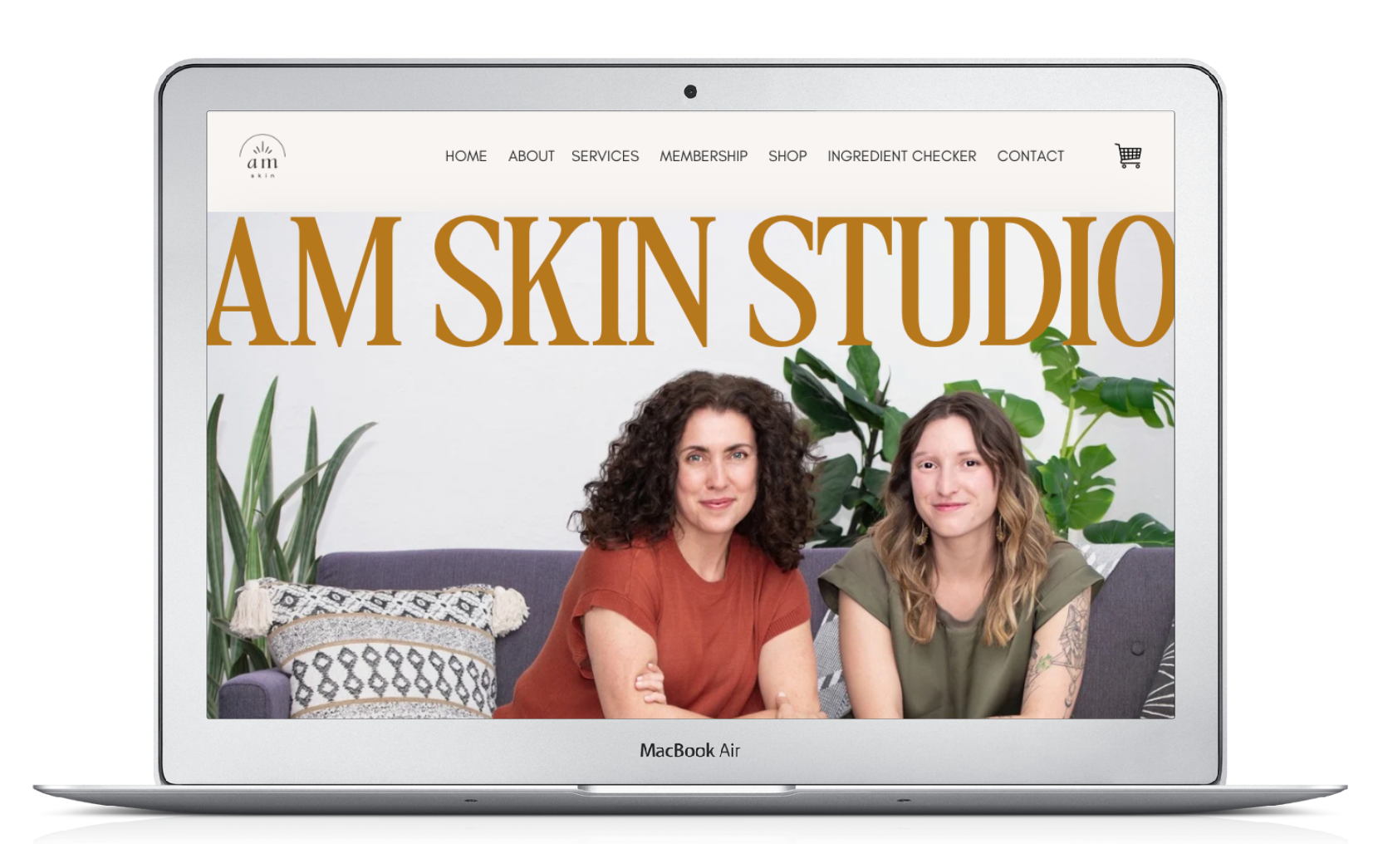 A laptop screen shows two women sitting on a couch. am skin studio