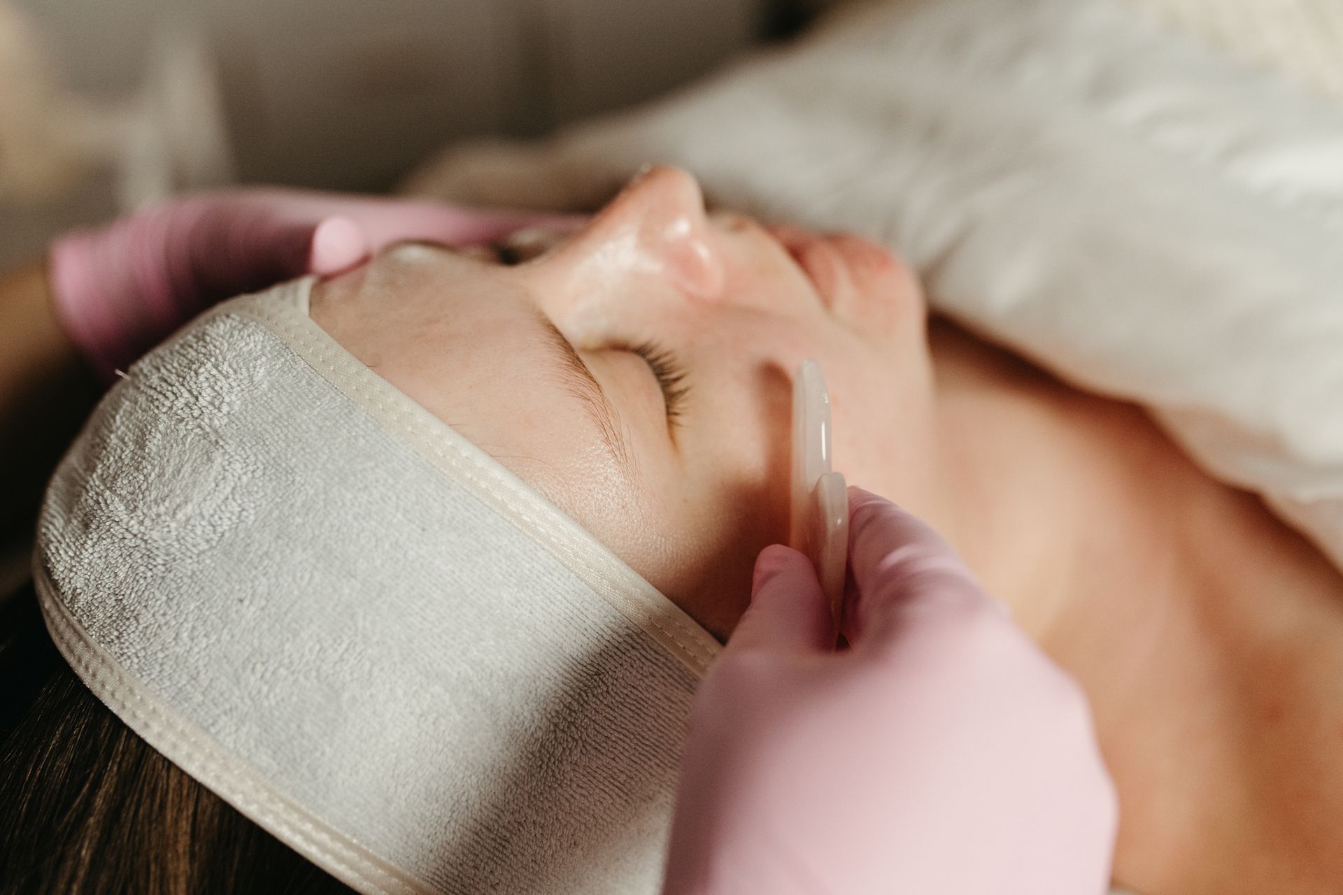 A person receiving a facial treatment with a brush and a towel wrapped around the head.