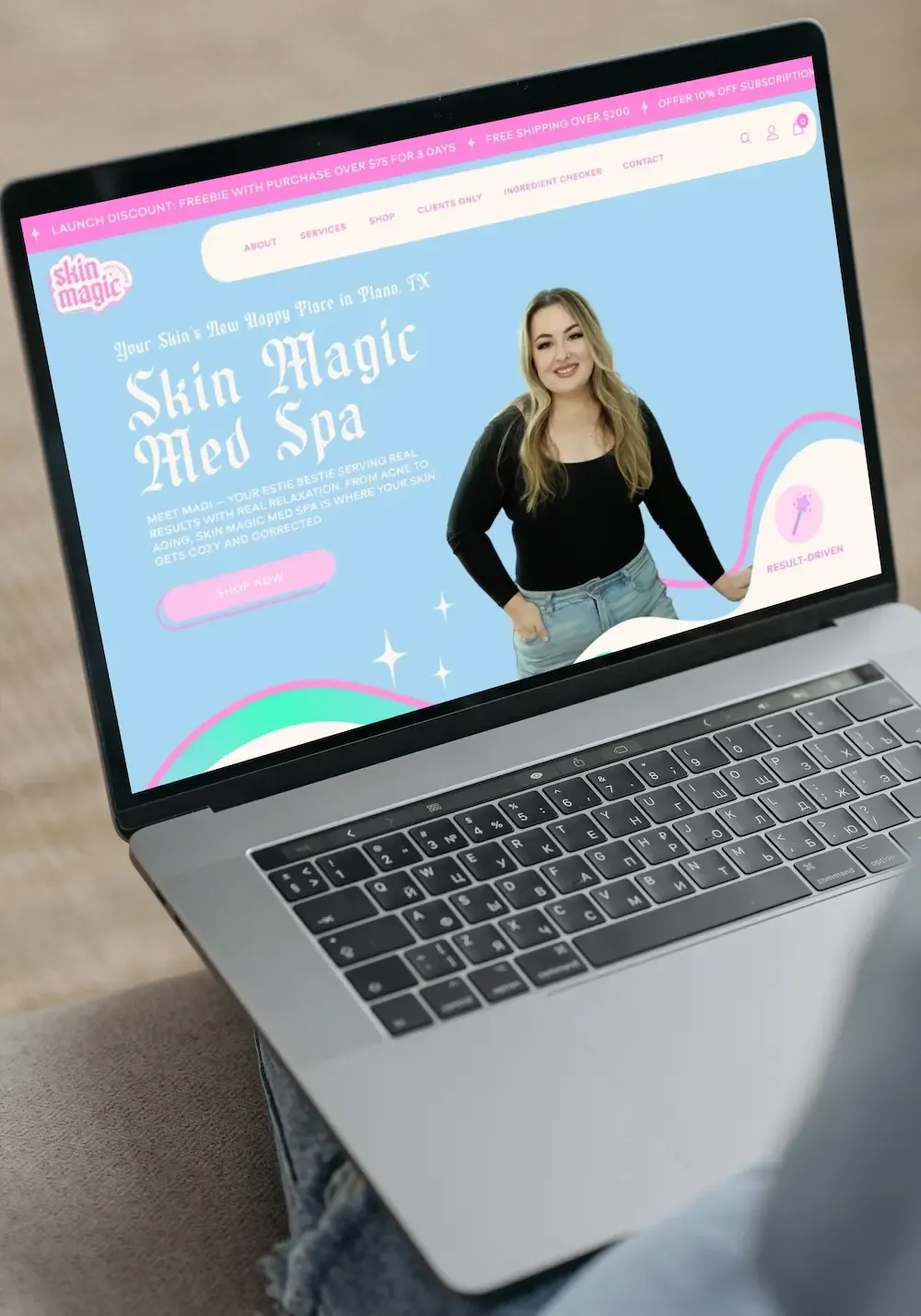 Laptop displaying a pastel website for “Skin Magic Med Spa” with a woman in black on the screen
