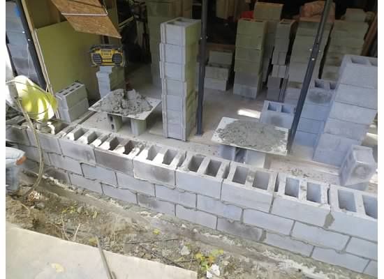 Construction site with cinder blocks, mortar, and stacks of building materials.