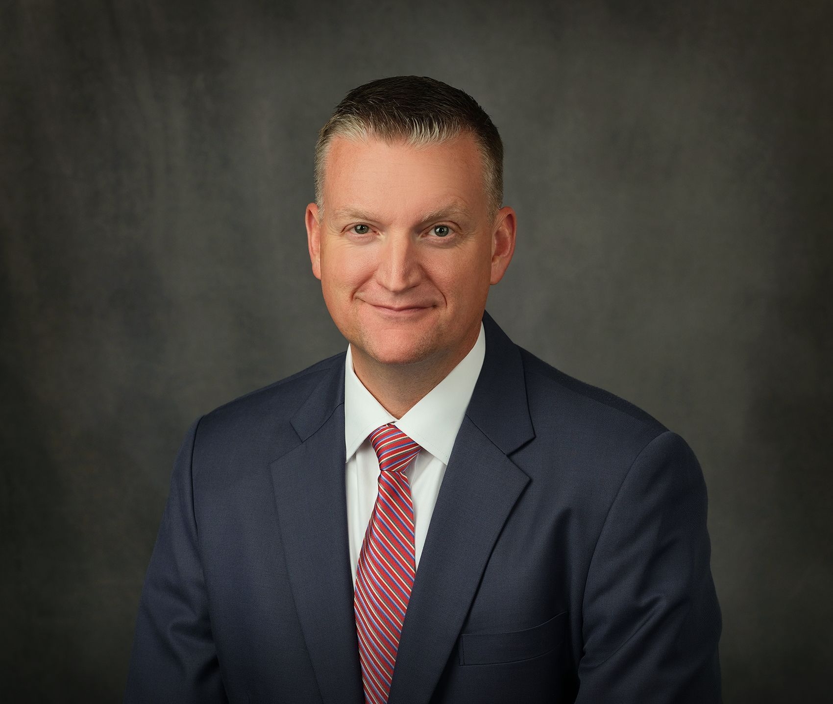 A man in a suit and tie is smiling for the camera.