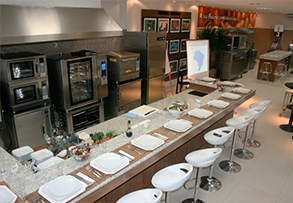 Una cocina con una larga encimera llena de platos y taburetes.