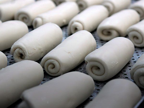Un montón de panecillos blancos están sobre una bandeja de metal.