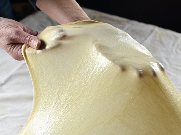 Una persona está estirando un trozo de masa sobre una mesa.
