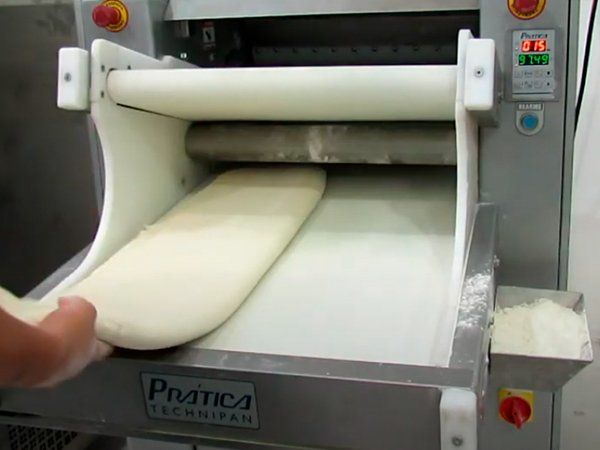 Una persona está amasando masa en una máquina que dice practica