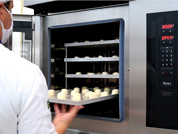 Un hombre está sacando una bandeja de comida de un horno que dice abierto.