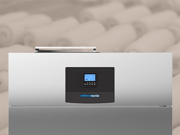 Un refrigerador de acero inoxidable con pantalla digital se encuentra frente a una pila de toallas.
