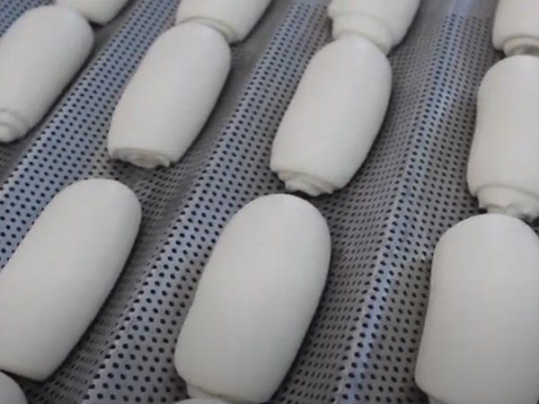 Un montón de cilindros blancos están alineados en una bandeja.