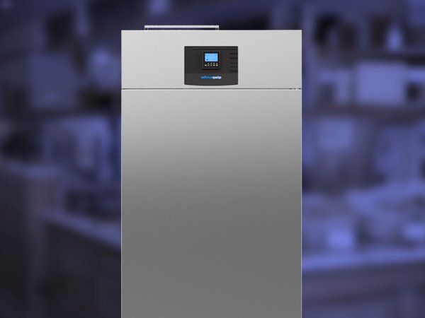 Un refrigerador de acero inoxidable está en una habitación oscura.