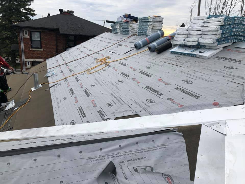 Main gantée utilisant un marteau pour fixer des bardeaux sur un toit lors de travaux de réparation